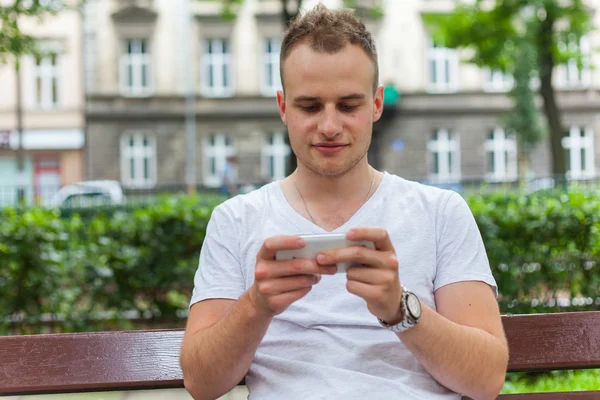 Bonito homem no parque usando smartphone . — Fotografia de Stock