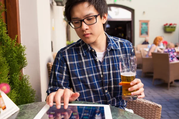 Člověk pije pivo a použití počítače tablet pc — Stock fotografie