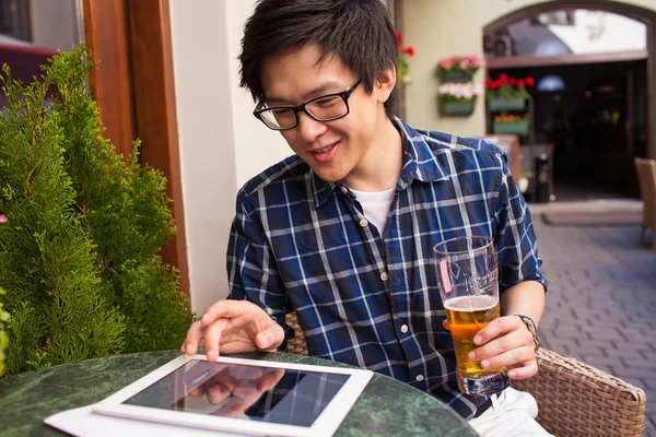 Člověk pije pivo a použití počítače tablet pc — Stock fotografie