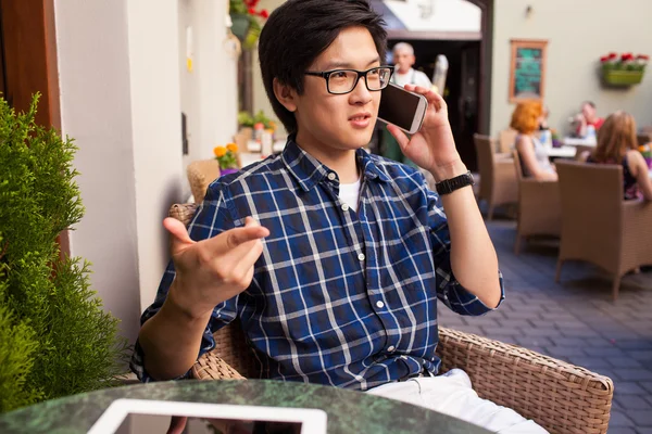 Asian man talking by phone in cafe — Stock Photo, Image