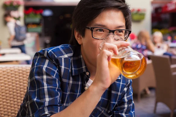 Asian man drinking beer in a bar