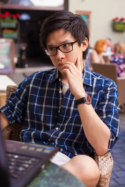 Asian man with laptop in a summer cafe — Stock Photo, Image