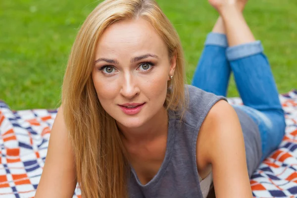 Blonde vrouw liggen in park op deken — Stockfoto