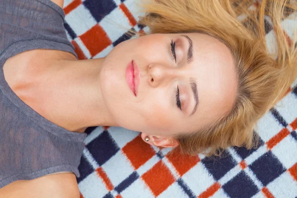 Blonde woman lying in park on blanket — Stock Photo, Image