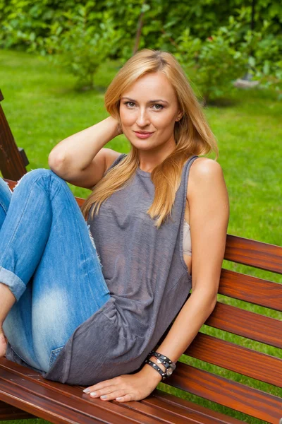 Mulher sentada no parque no banco de madeira — Fotografia de Stock