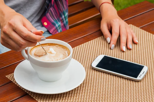 Женские руки с мобильным телефоном и кофе — стоковое фото