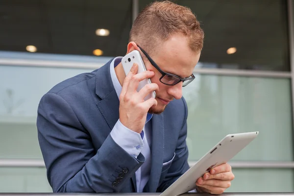 Zakenman met behulp van de mobiele telefoon en tablet pc — Stockfoto