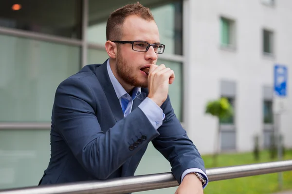 Businessman with beard eating candy bar — Stock Photo, Image