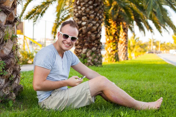 Turist under palm med mobiltelefon — Stockfoto