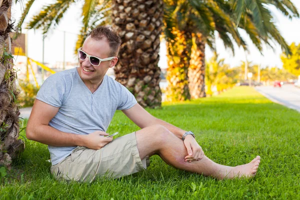 Turist under palm med mobiltelefon — Stockfoto