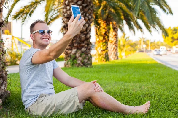 Tourist  under palm  with mobile phone — Stock Photo, Image