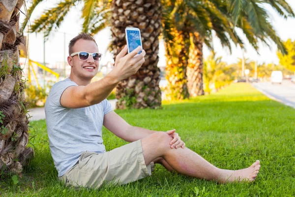 Tourist  under palm  with mobile phone — Stock Photo, Image