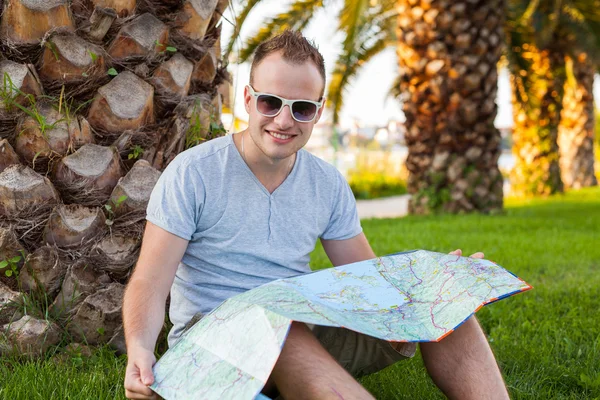 Turista sob palma e olhando para o mapa . — Fotografia de Stock