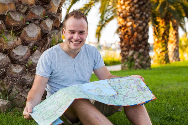 Tourist  under palm  and looking at map. — Stock Photo, Image