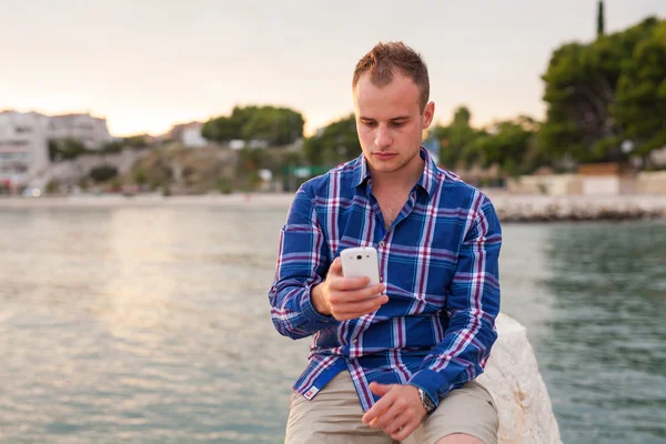 Muž pomocí telefonu na pobřeží — Stock fotografie