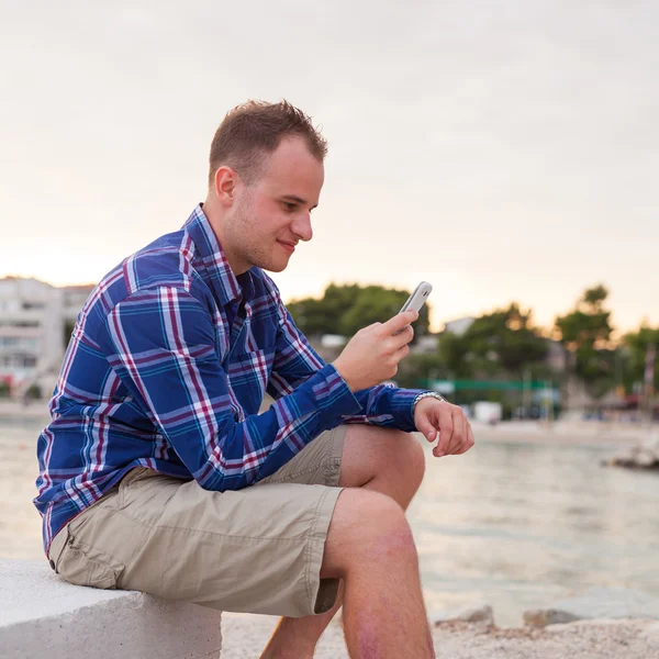 Hombre usando el teléfono en la orilla del mar —  Fotos de Stock