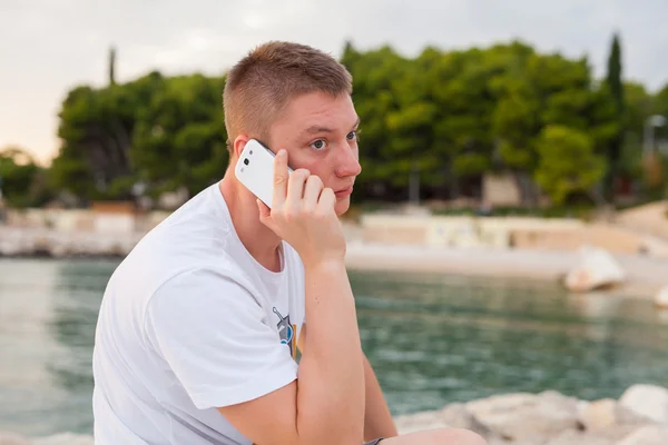 Man met behulp van telefoon aan kust — Stockfoto