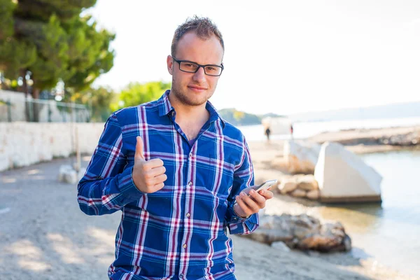 Turista s mobilním telefonem na pláži. — Stock fotografie