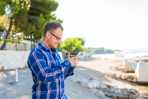Turist med mobiltelefon på stranden. — Stockfoto