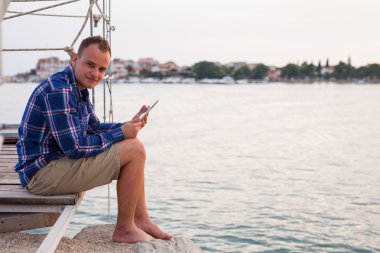Adamın yanında deniz ve tablet kullanma.