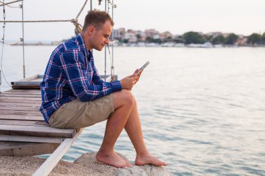 Adamın yanında deniz ve tablet kullanma.