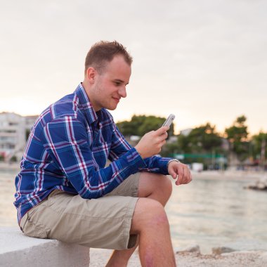 Sahil üzerinde telefonu kullanan adam
