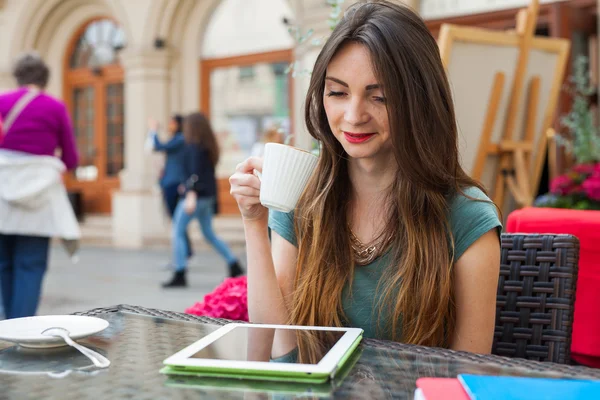 Девушка сидит в кафе и пьет кофе — стоковое фото