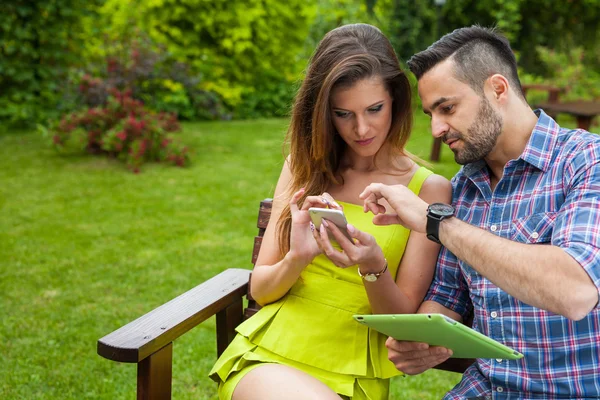 Coppia seduta sulla panca e utilizzando tablet — Foto Stock