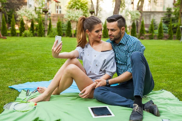 Couple assis sur le blaket et prenant selfie — Photo