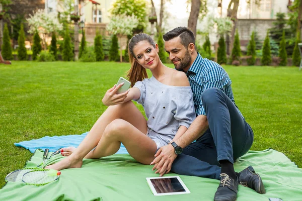 Couple sitting on the blaket and taking selfie — Stock Photo, Image