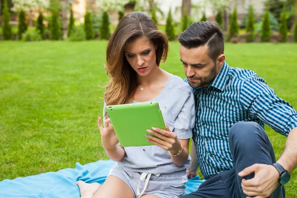 Couple using tablet  on the blanket — Stock Photo, Image