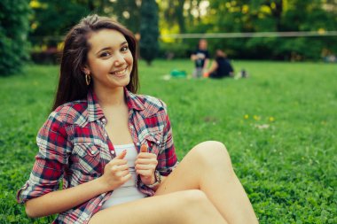 Çimenlerin üzerinde oturan kumral kız