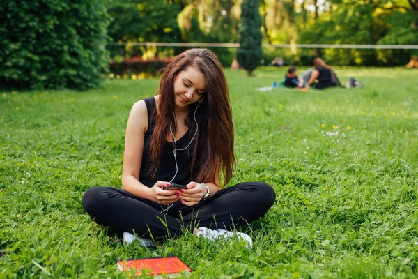 Kvinna lyssna musik i parken — Stockfoto