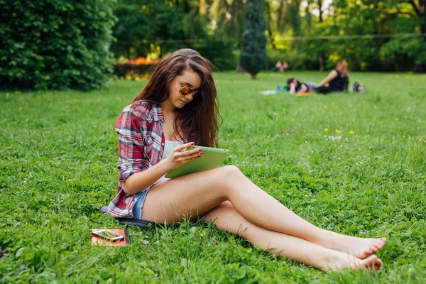 Frau benutzt Tablet im Park — Stockfoto