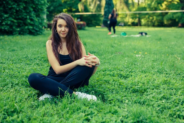 Hnědé vlasy dívka sedící v trávě — Stock fotografie