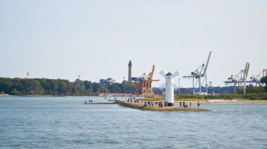  Swinoujscie şehrinin dönüm noktası olan değirmen fenerindeki turistler, 12 Eylül 2020 'de limanın arka planında                              