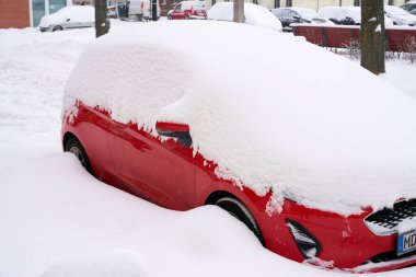 Almanya 'nın Magdeburg şehrinin merkezindeki bir caddede kışın kar altında kalmış arabalar.                               