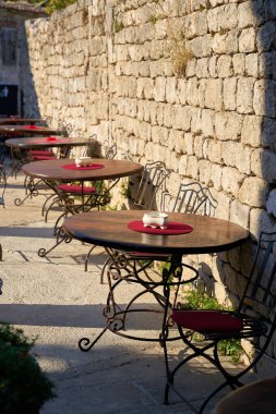   Hırvatistan 'ın eski Krk kasabasındaki tarihi kent duvarındaki bir restoranın masaları                             