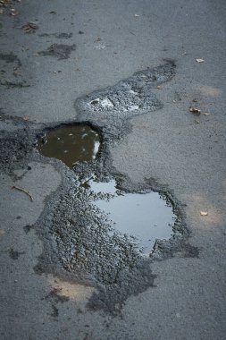   Bir yolun asfaltında, yağmur sularıyla dolu bir çukur.                             