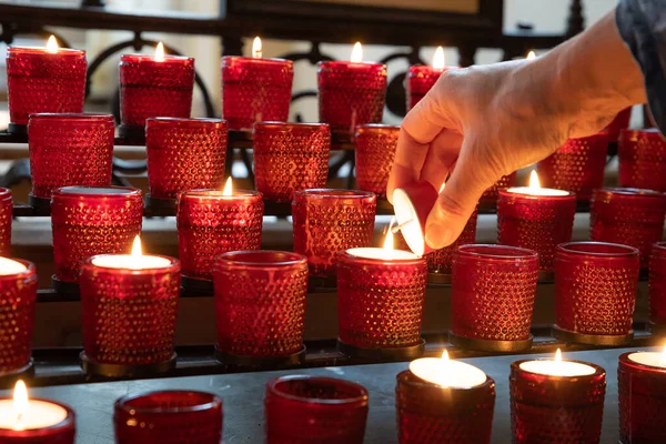 Encender una vela roja de sacrificio en una iglesia — Foto de Stock