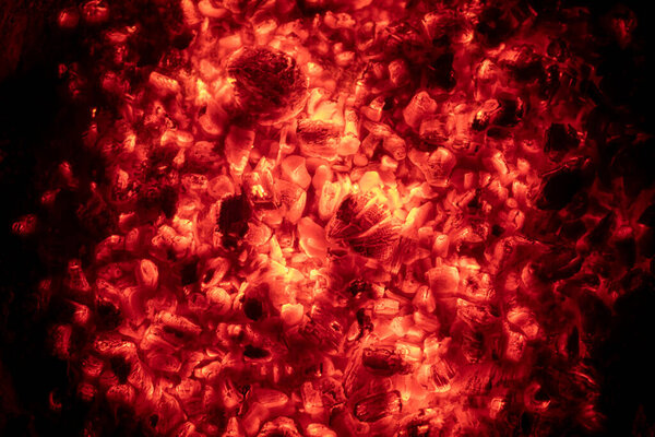 Red glowing charcoal in a campfire against a black background