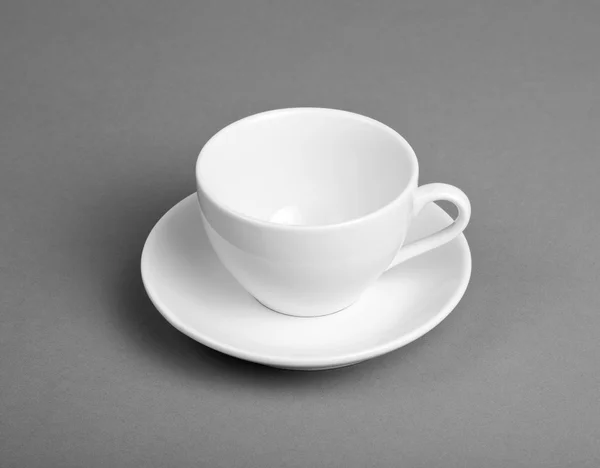 Tasse blanche et soucoupe sur fond gris . — Photo