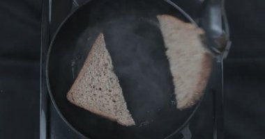 Bir ev aşçısı kahvaltı hazırlar. İki parça ekmek tereyağında cızırdıyor. Şef tost yapıyor.