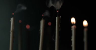 Bulanık arkaplanda mumlardan duman çıkıyor.