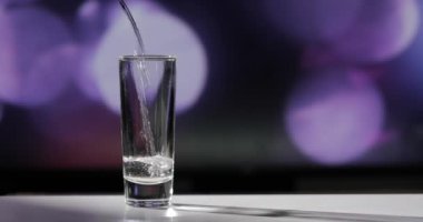 Barmen shot bardaklarına votka / tekila dolduruyor.