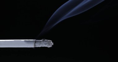 Siyah arka planda yanan bir sigara. Dünya Tütünsüz Günü