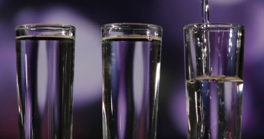 Barmen üç shot bardağına tekila dolduruyor.