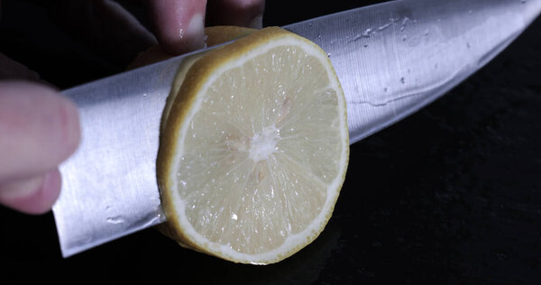 Мужские руки с ножом режут лимон на доске