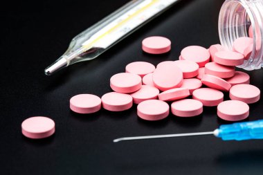 Siyah arka plandaki ilaç kutusundan pembe haplar dökülüyor.