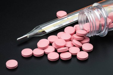 Siyah arka plandaki ilaç kutusundan pembe haplar dökülüyor.